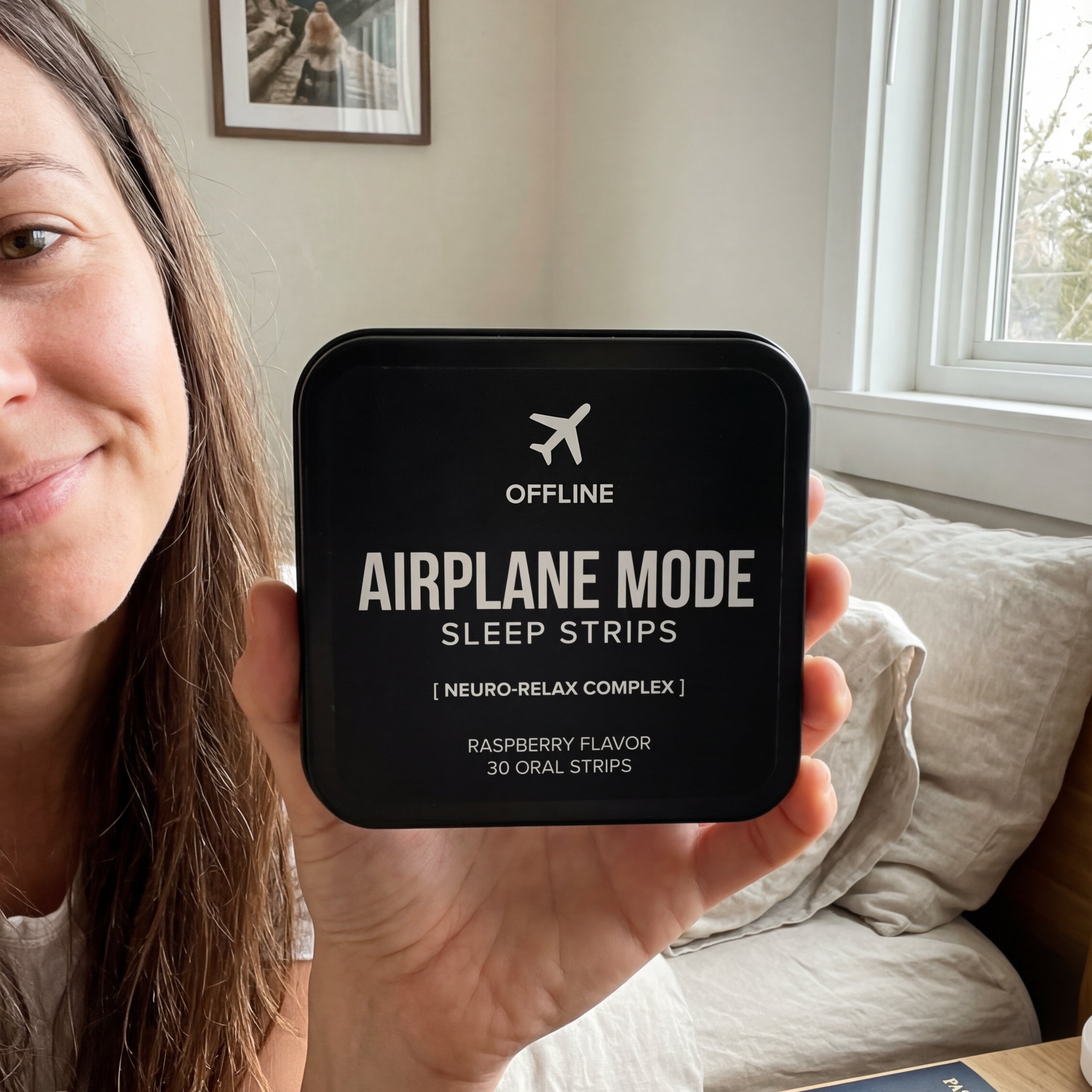 Person holding a container of 'Airplane Mode Sleep Strips' in a room with a couch and window.